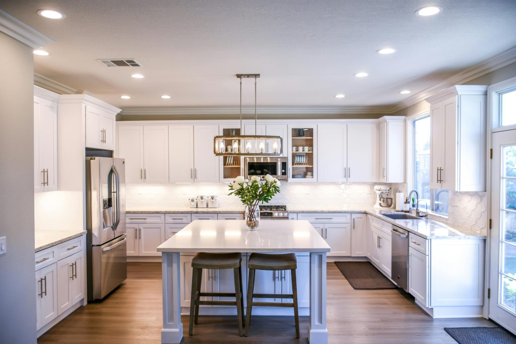 Modern kitchen interior with white cabinets, stainless steel appliances, and a central island featuring a vase of flowers, emphasizing a welcoming atmosphere for homebuyers considering gas safety and appliance checks in Wigan and Greater Manchester.